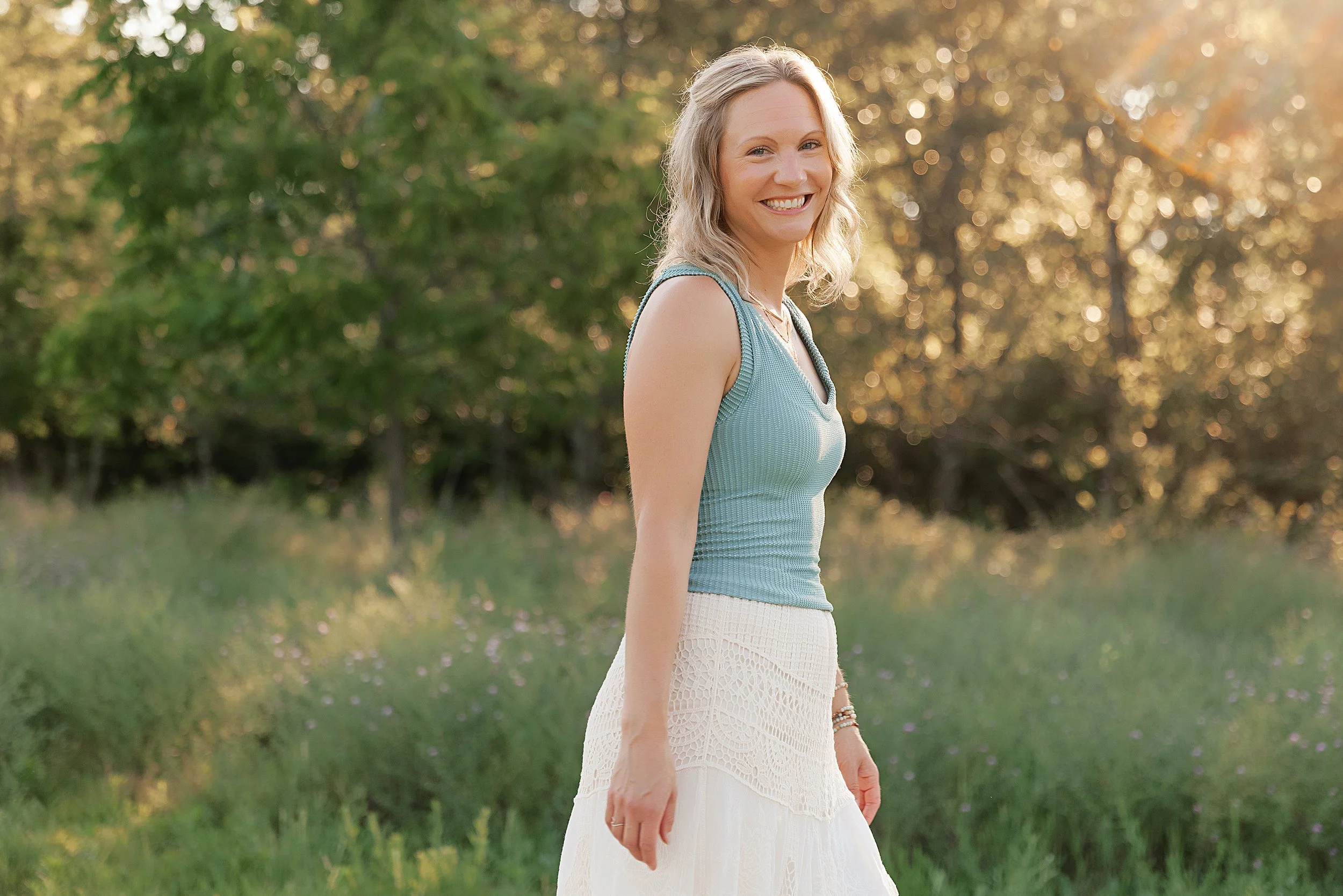 Brooke of Rooted Radiant Collective smiling outdoors at sunset, offering Reiki, nervous‑system support, and intentional living guidance