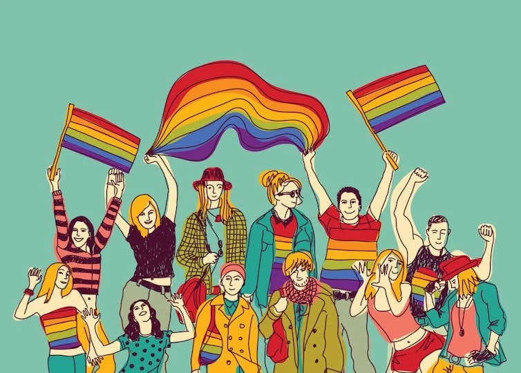 A diverse group of people celebrating LGBTQ+ pride, holding rainbow flags and wearing rainbow-colored clothing and accessories.