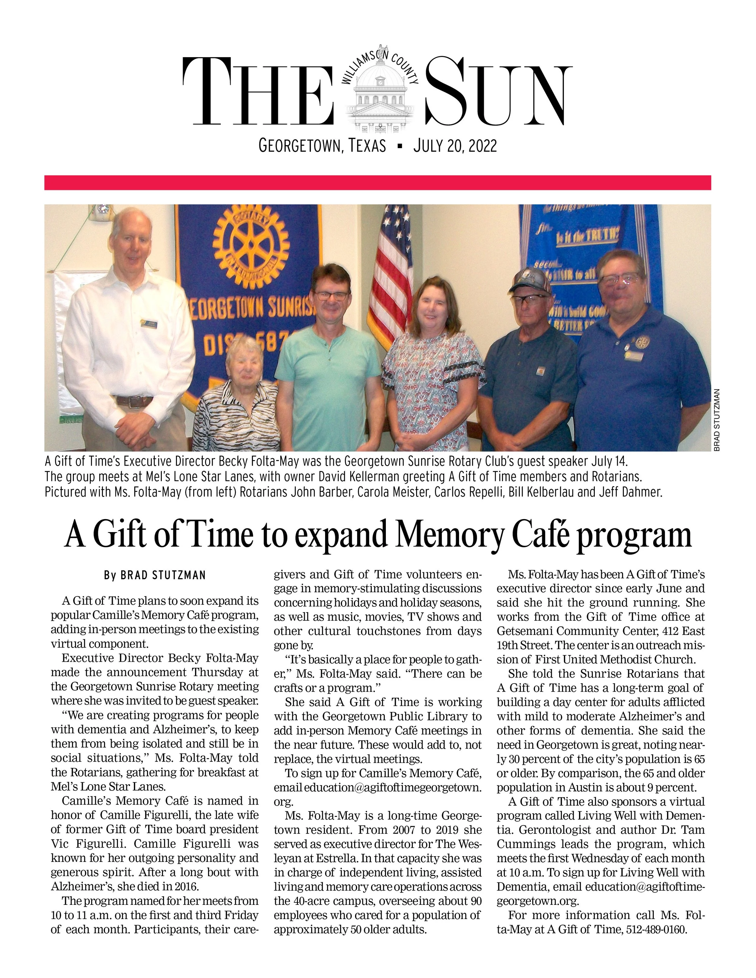 A newspaper article featuring a group photo of six people at a Rotary Club meeting, standing in front of Rotary banners and an American flag, with a headline about expanding Memory Café programs.