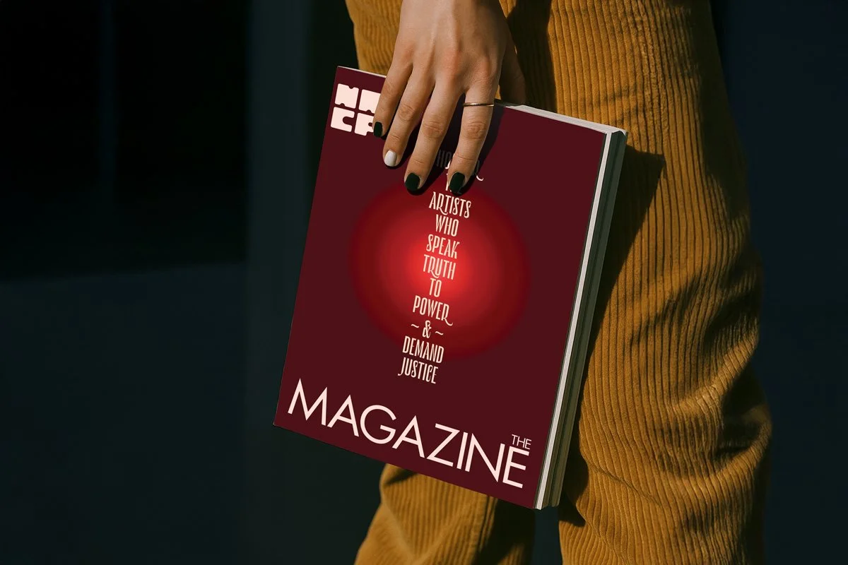 Close up of a person holding a copy of The Magazine down by their leg.