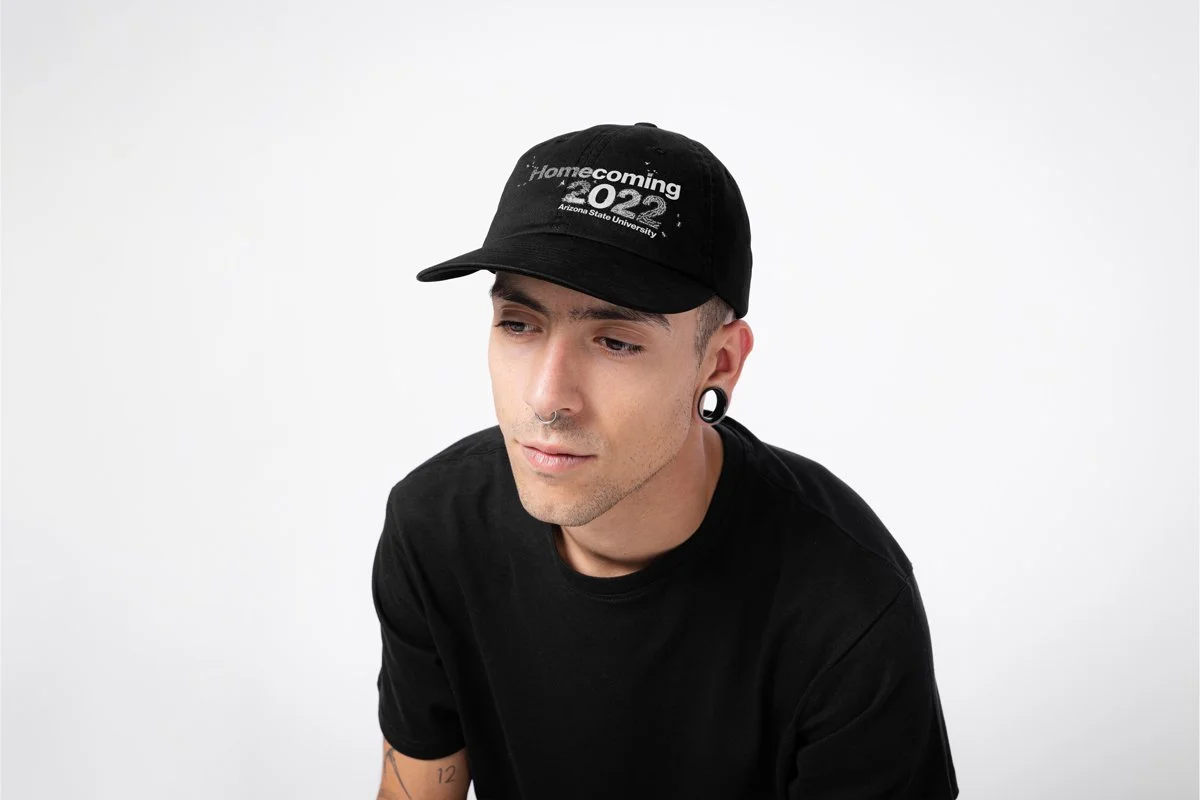 A man with gauges wearing a black hat that reads Homecoming 2022.