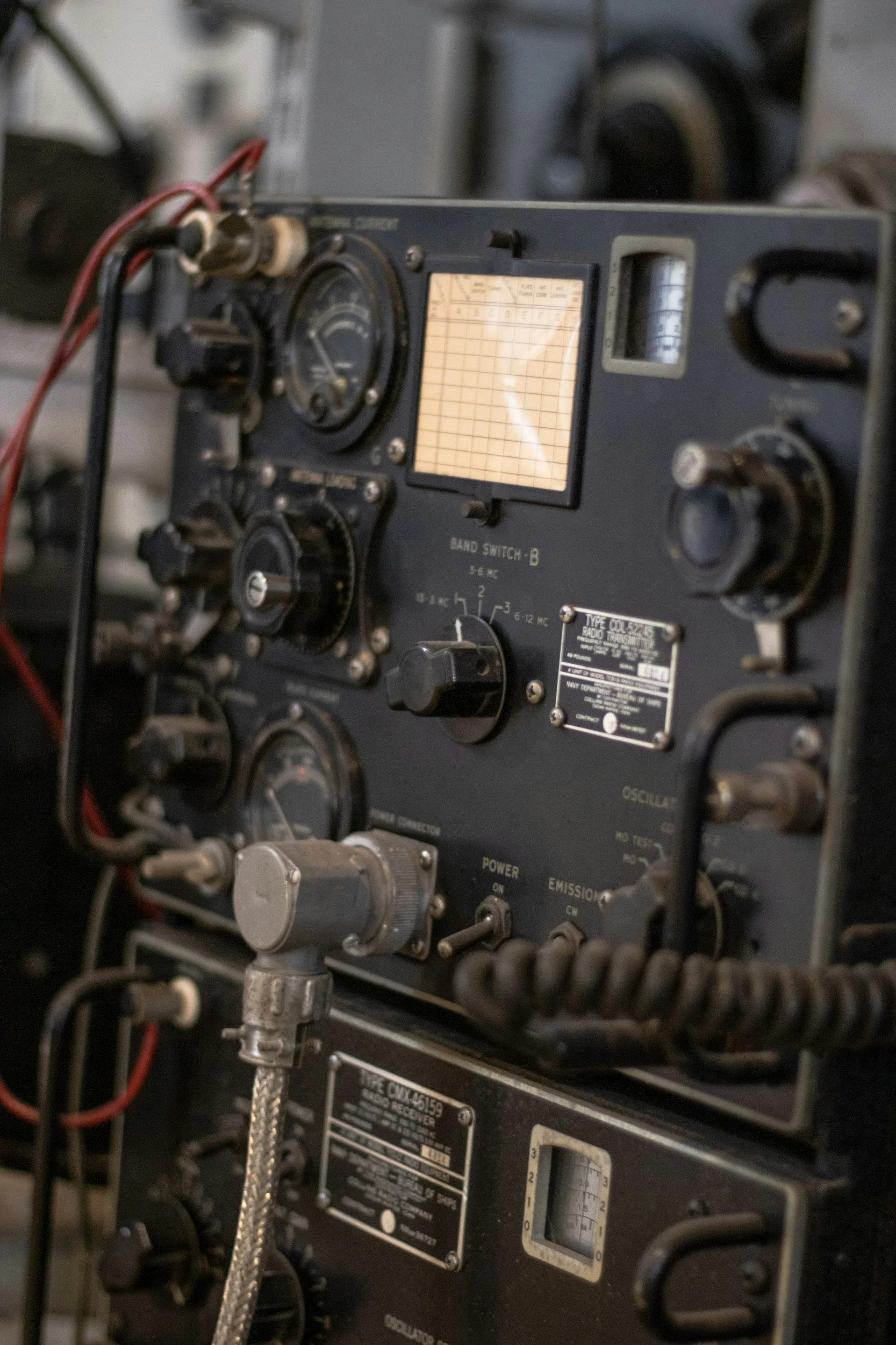 Close-up of vintage radio communication equipment, including dials, meters, and switches, with wires connected.