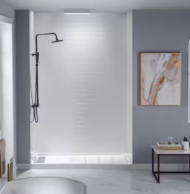 Modern bathroom with a walk-in shower featuring a black handheld showerhead, white tiled wall, and a small side table with toiletries, artwork on the wall.