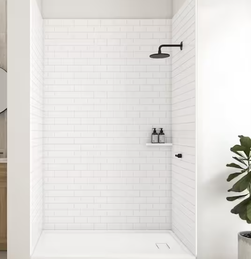 Minimalist white tiled walk-in shower with black showerhead and fixtures, and a small shelf with toiletries.