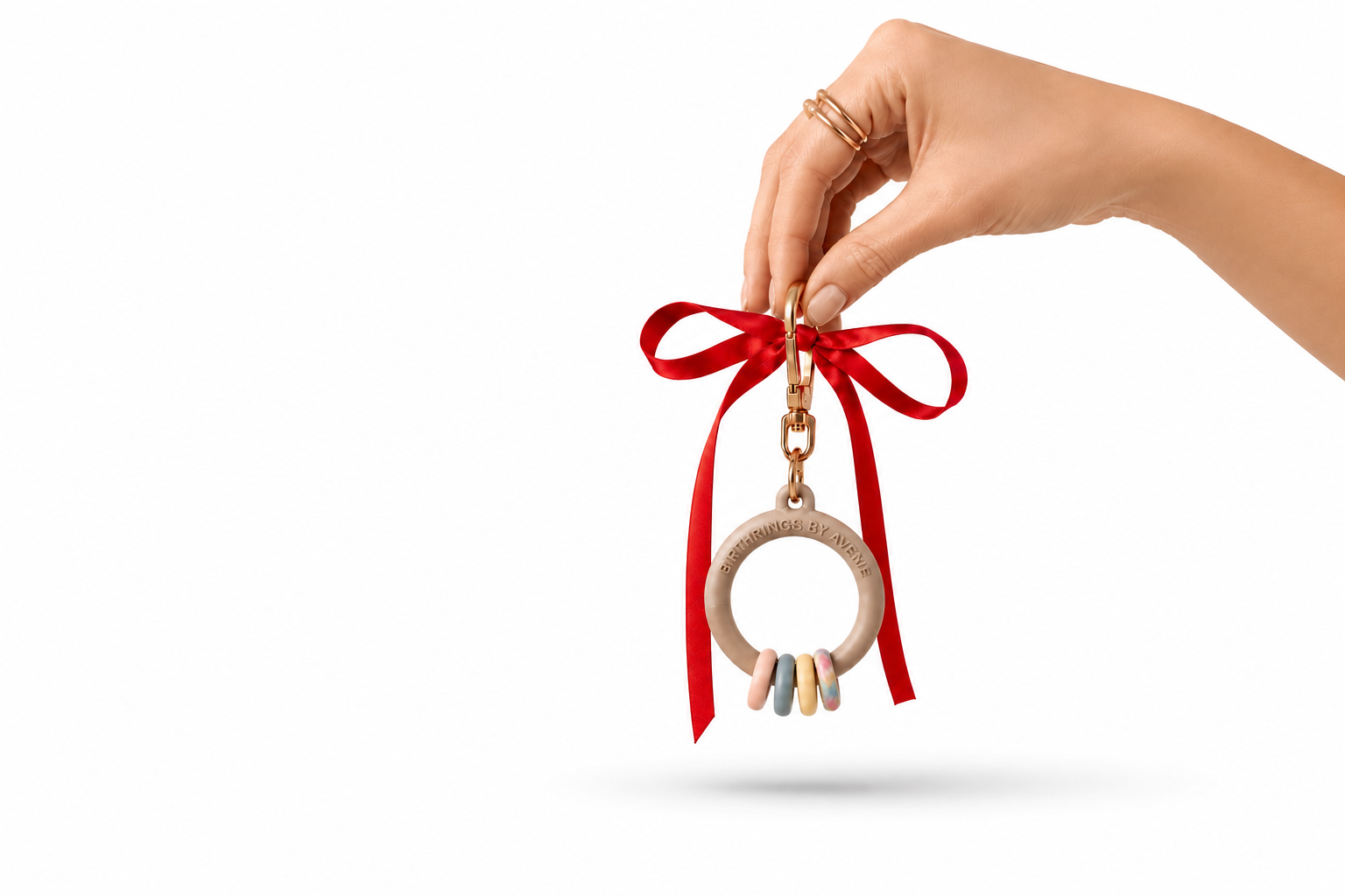 Hand holding BirthRings keepsake with colorful token rings attached.