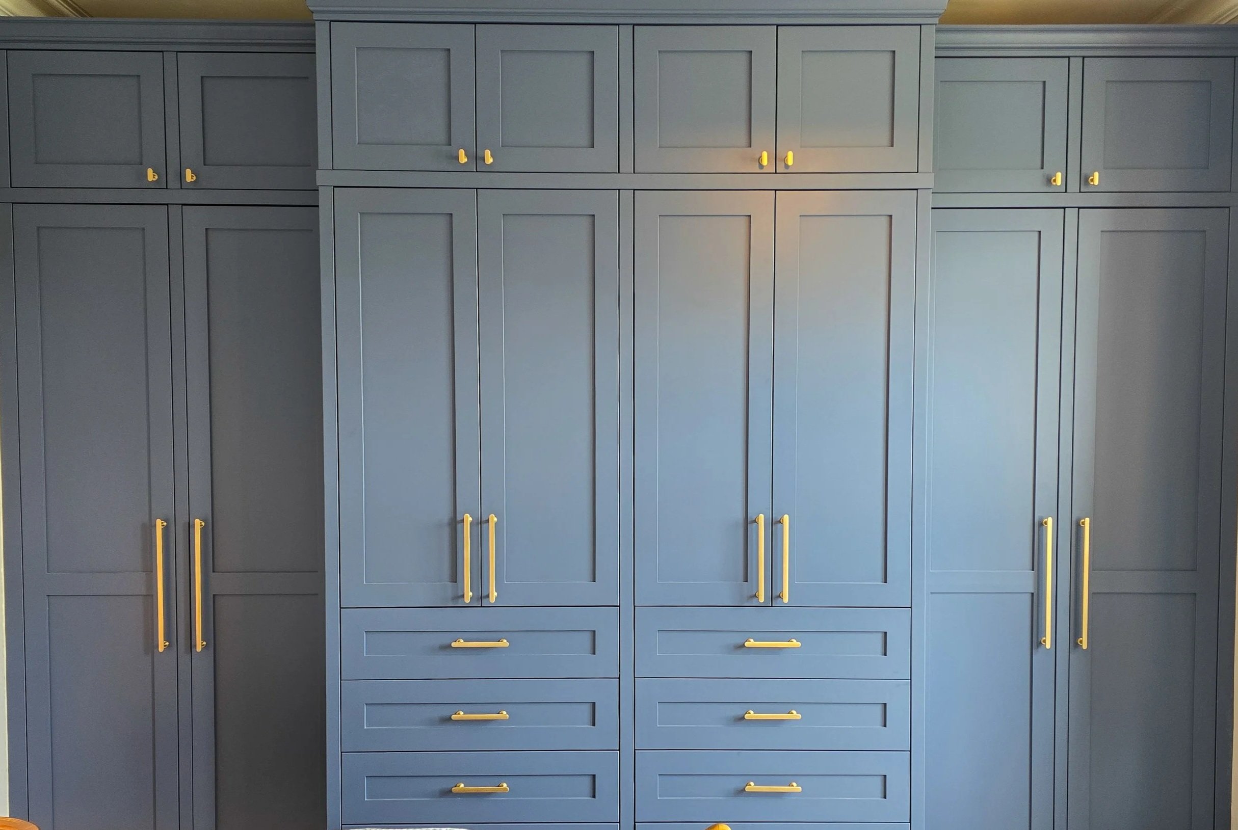 Large built-in gray cabinet with multiple doors and drawers, featuring yellow handles, in a room with a yellow ceiling.