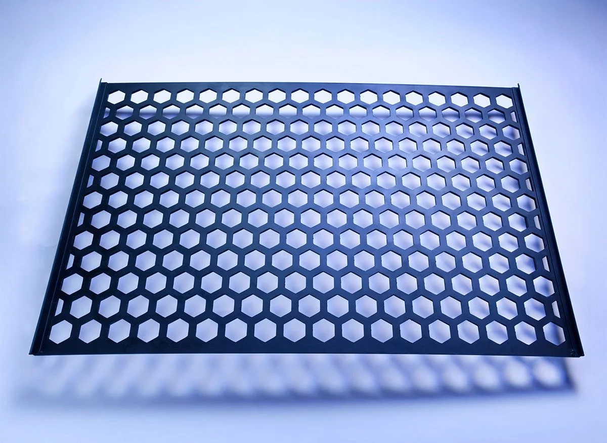 Black plastic grid with hexagonal holes on white background.