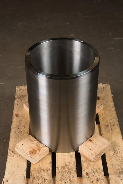 A cylindrical stainless steel object placed on a wooden pallet.