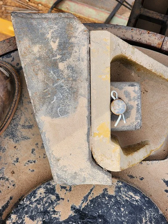 Close-up of a dusty industrial saw or grinding machine with a clamp mechanism.