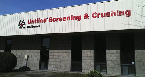 The exterior of a building with a sign that reads 'Unified Screening & Crushing California' in red letters.