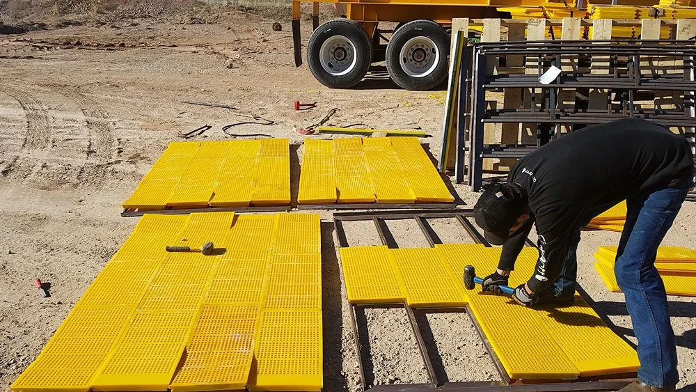 A construction worker is assembling urethane panels at a construction site, with tools and construction materials around.