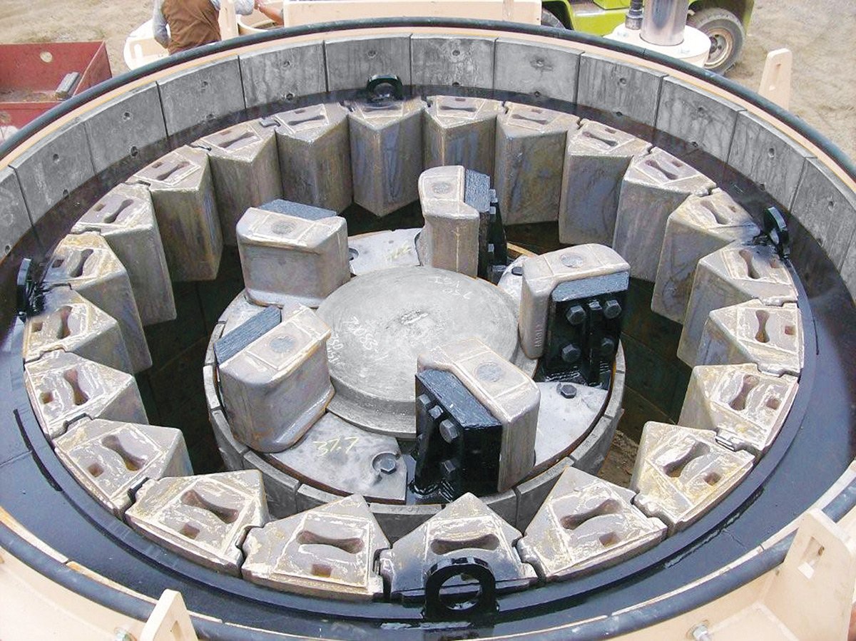 Close-up of a large mechanical part with a circular array of metal blocks around a central rotating dish, likely a mold or industrial component under construction or maintenance.