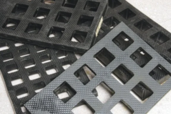 Close-up of rectangular black plastic grid sheets with square and rectangular cutouts.