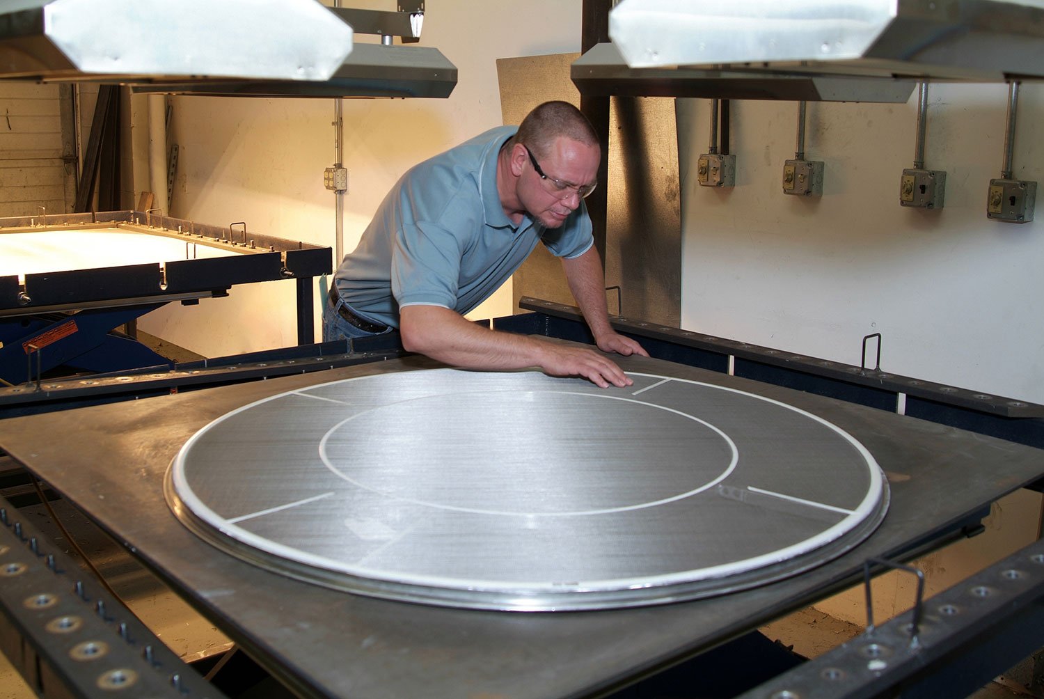 A man working on a large industrial device with a circular design in a workshop
