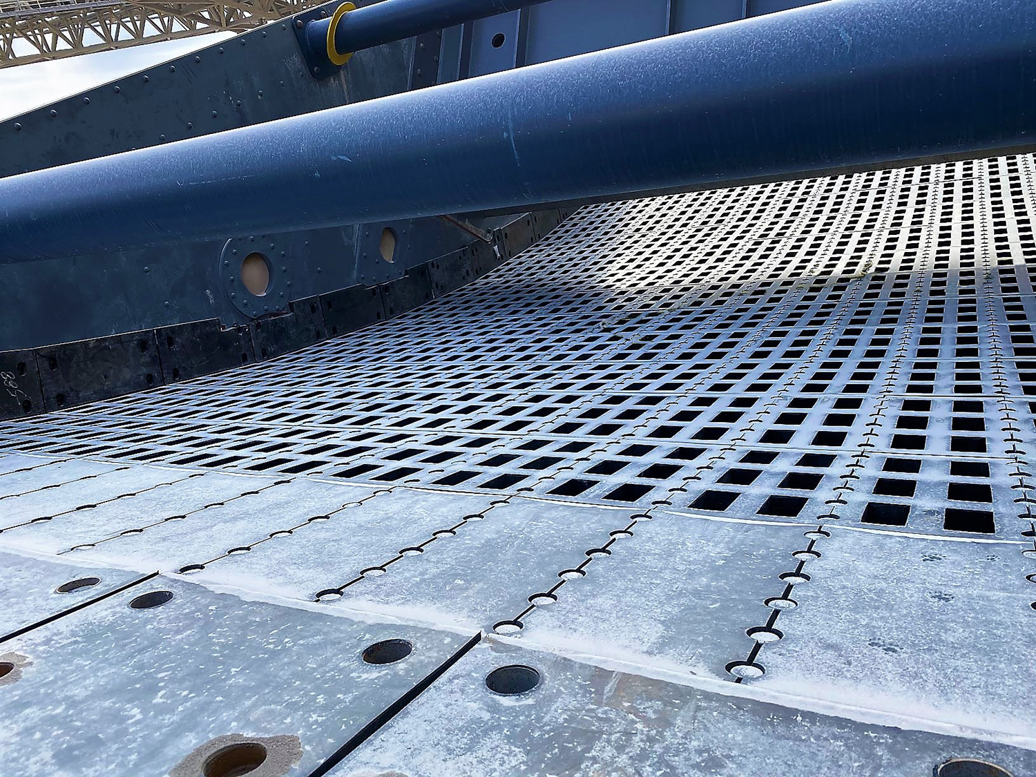 Close-up of a metal platform with a grated surface, part of a larger industrial or mechanical structure