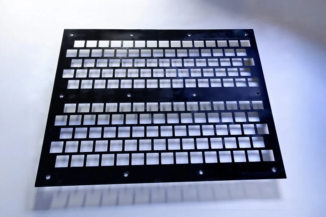 Black grid panel with multiple square cutouts, placed on a white surface.