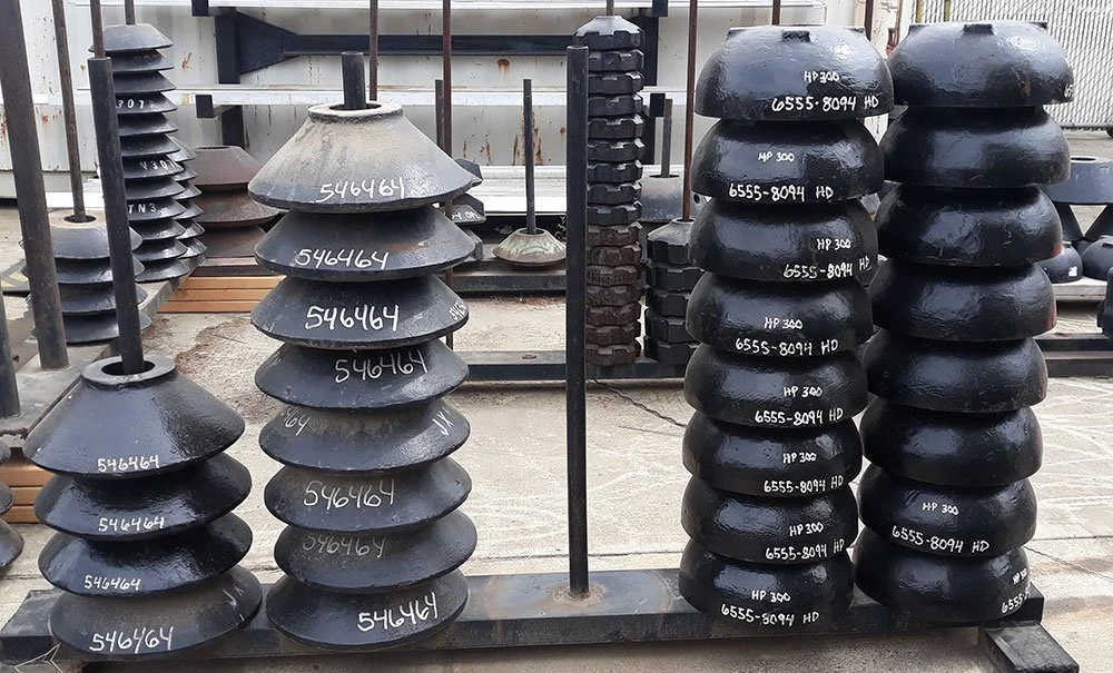 Stacks of black railroad wheel tires and weights on a metal rack outside.