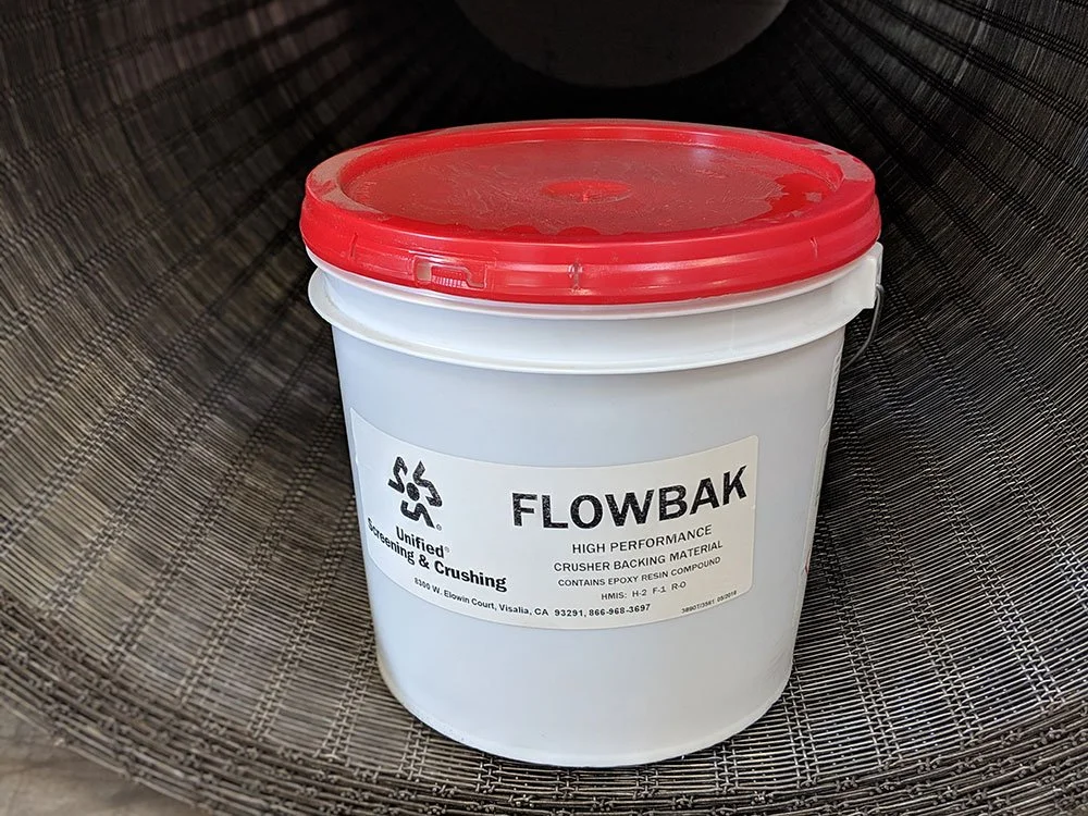 A white bucket with a red lid labeled 'FLOWBAK' containing epoxy resin for backing material.