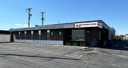 Exterior of a financial building with a sign reading 'Bank of America Financial.' An empty parking lot in front and power lines in the background.