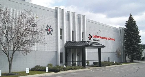 United Screening & Crushing facility in Minnesota with a white building, a tree, and parking lot.