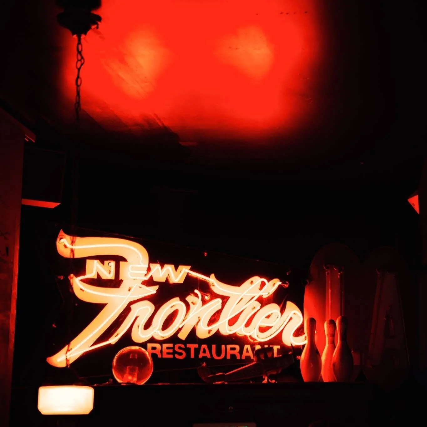 Neon sign reading 'Torchy's Restaurant' with hanging chili peppers and a glowing red overhead light.