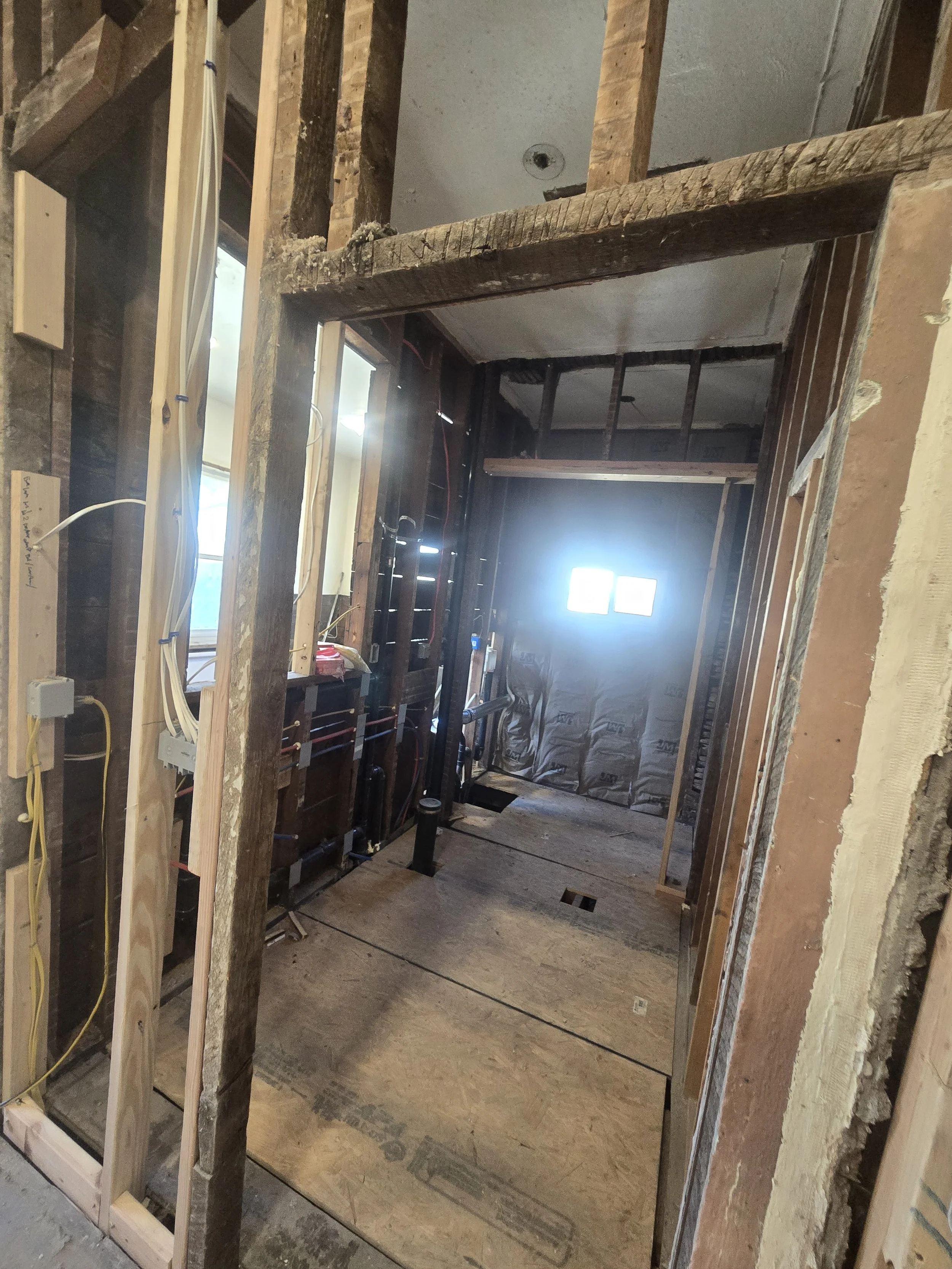 Indoor construction site showing framing and wiring in progress for a building renovation.