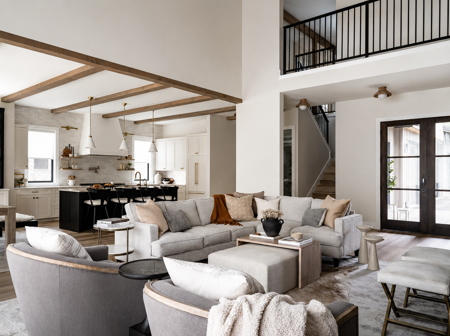 Spacious open-concept living room and kitchen with neutral decor, wooden beams, and large windows and glass door letting in light.
