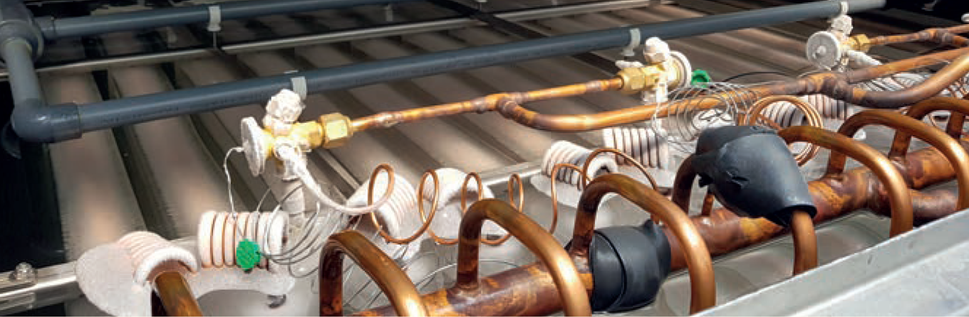 Close-up of industrial pipes and valves with insulation and wiring inside a machinery unit.