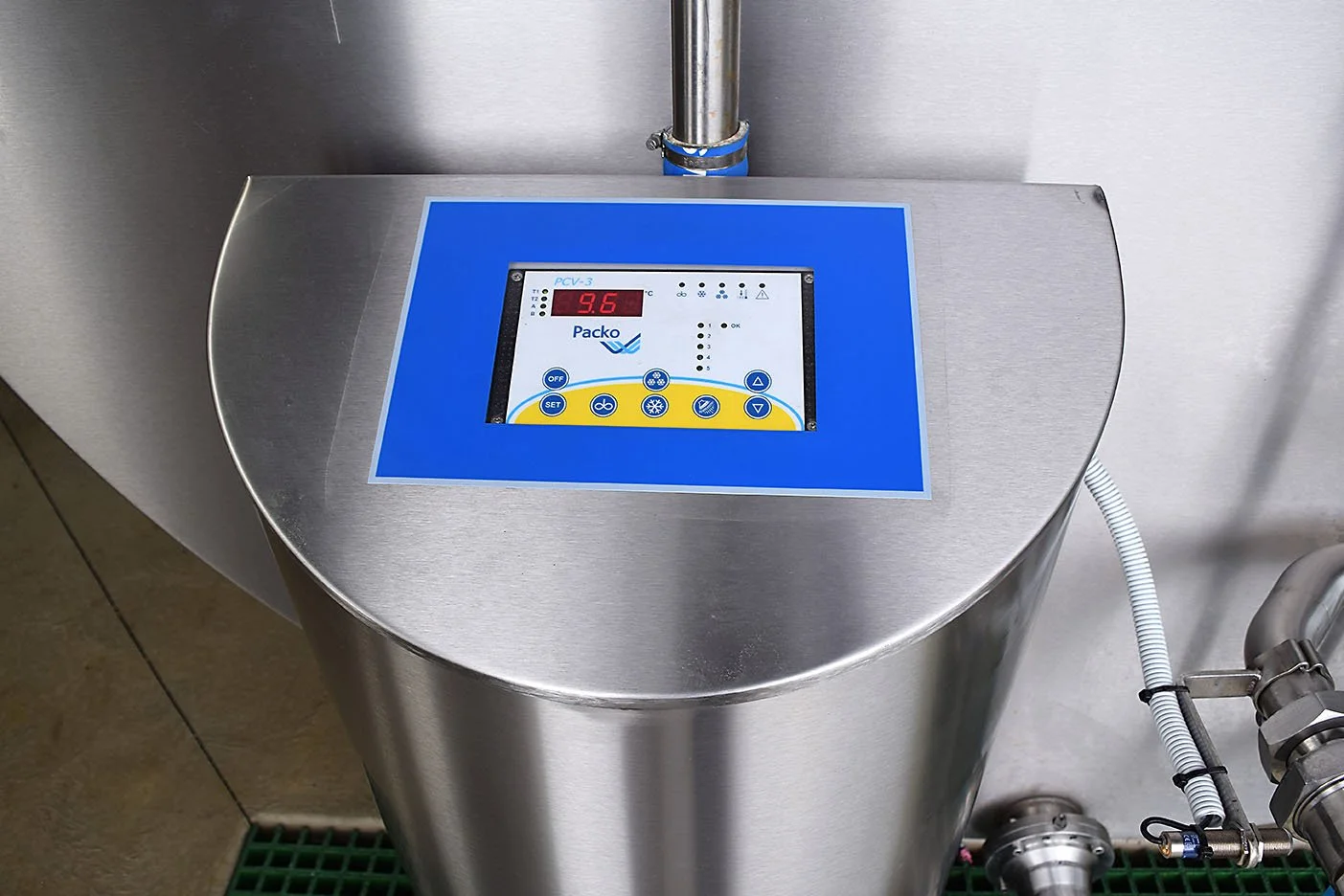 Stainless steel container with a digital control panel on top displaying a temperature of 3.6°C, connected to pipes and wires.