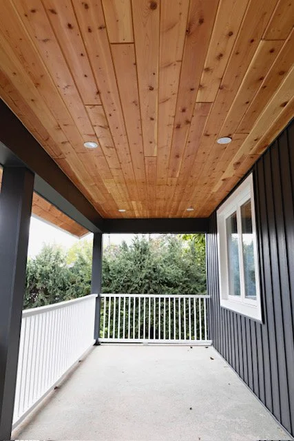 Concrete front porch with cedar lined ceiling with built in lights and wooden railing in St. Catharines