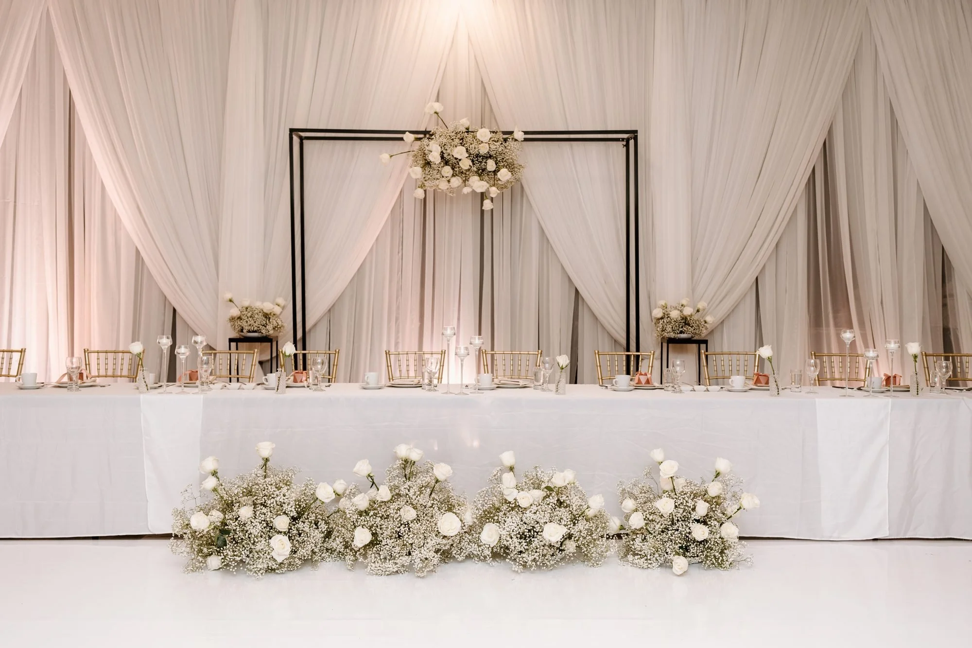 Wedding head table with ivory drapery backdrop and white florals by Real Event Designs, London Ontario