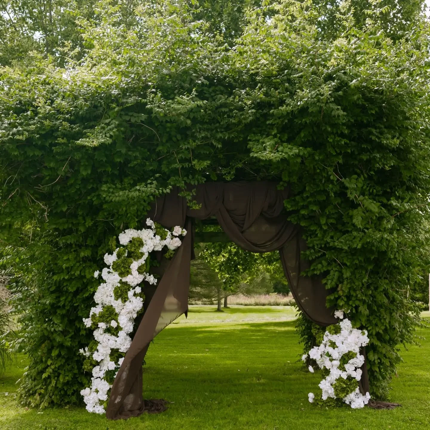 Some of the best ceremony spaces are the ones nature already built. 🌿

Mocha silk draping and a cascade of white hydrangeas and roses, tucked into an ivy-covered arbour. Simple, romantic, and made for this exact spot.

Now booking 2027 weddings. DM 