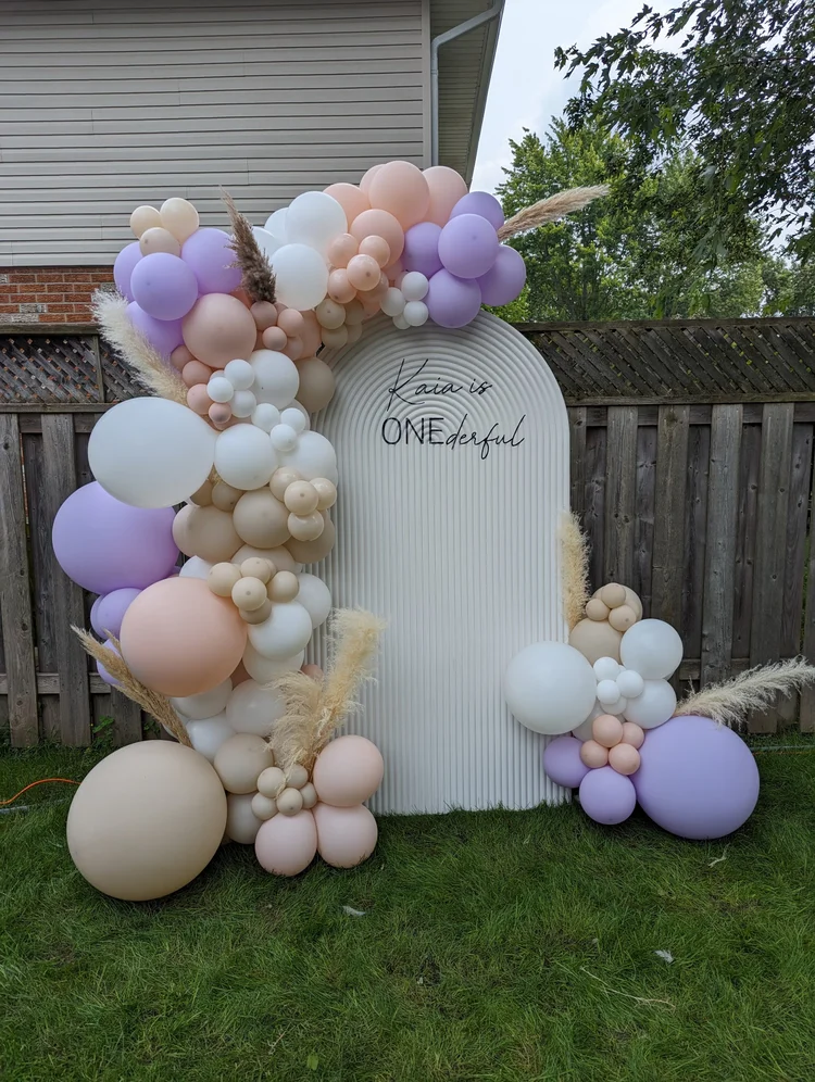 Solid arch backdrop with lilac and peach balloon garland and custom vinyl lettering