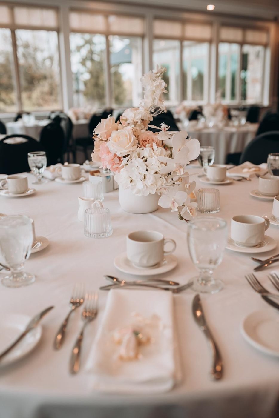 Blush and ivory floral centrepiece with orchids on a wedding reception table, styled by Real Event Designs in London Ontario