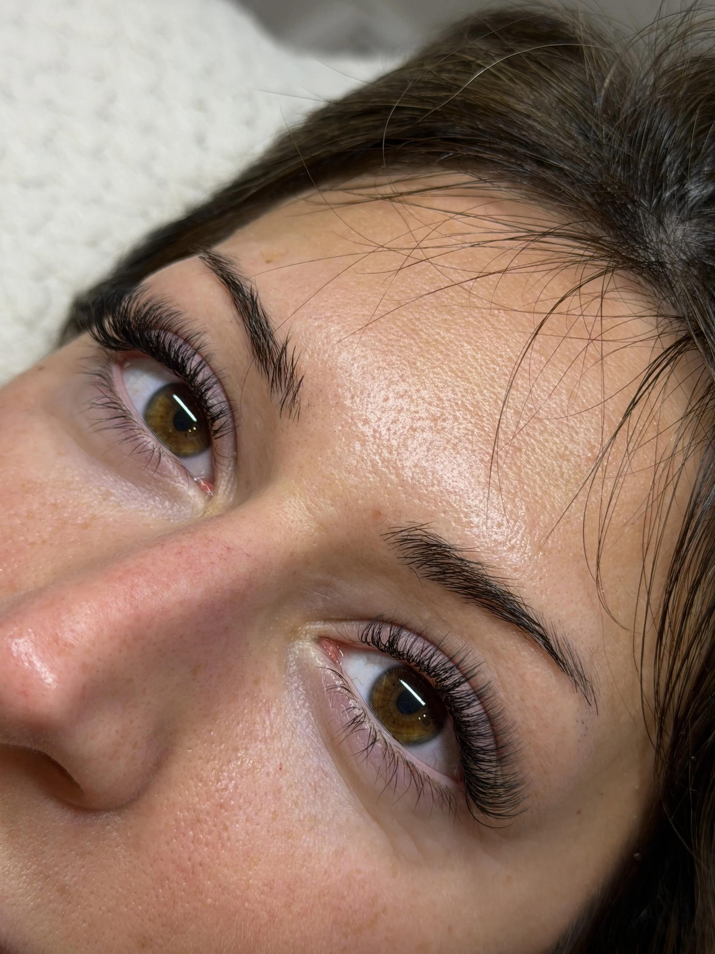Close-up of a person's face, focusing on one eye and eyebrow, with brown hair visible above the forehead.