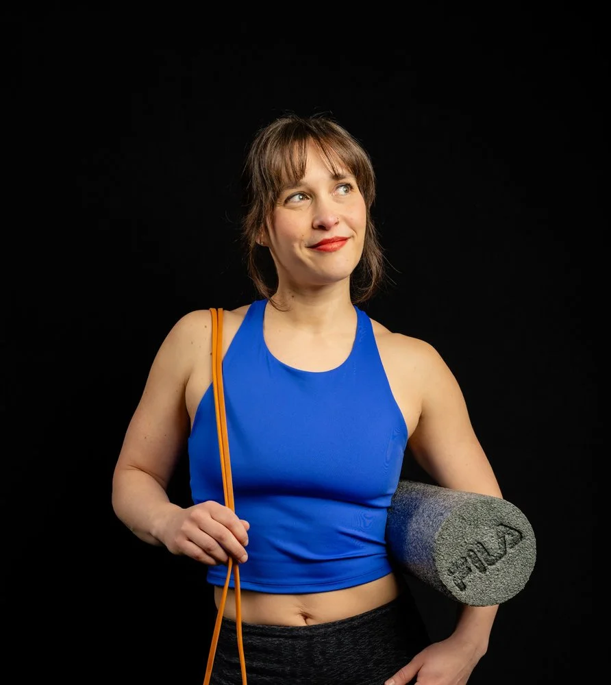 Nutrition and wellness coach Jamie holds workout gear and smiles looking off camera.