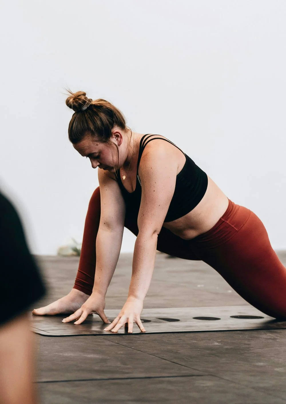 A middle aged woman stretches in a yoga pose as a participant in a virtual women's health coaching session.
