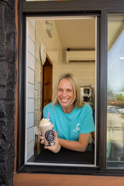 Owner haylee mensonides holding a milkshake in the drive thru window