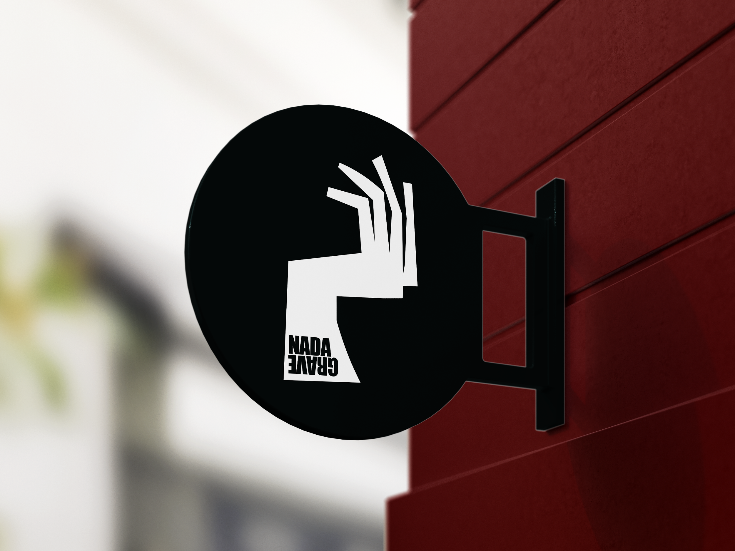 A black circular sticker with white text and graphics is attached to a red surface. The sticker says "GRAFE NADA" and features a design resembling a clenched fist or hand, with lines extending from the hand's wrist area.