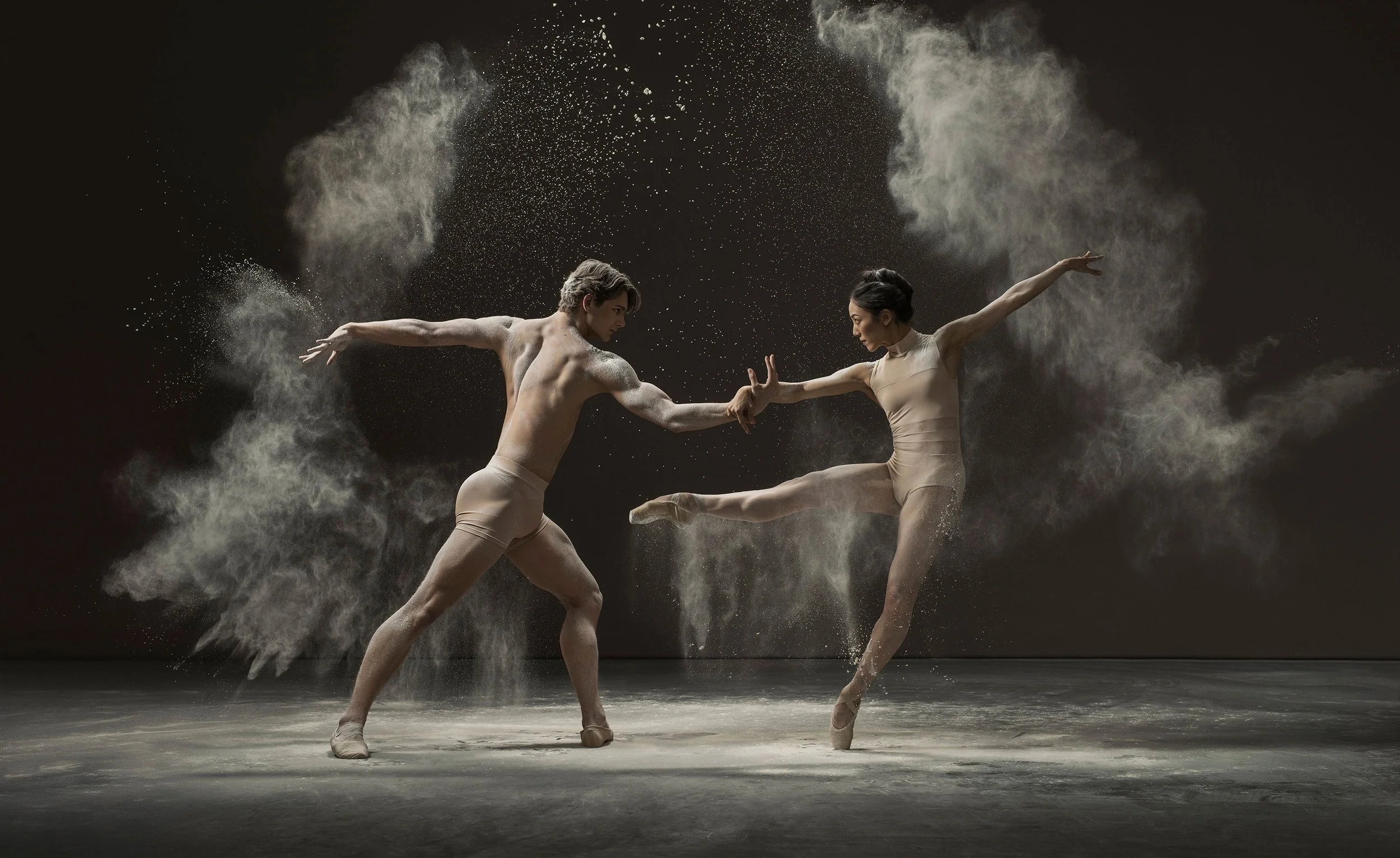 Conceptual ballet duet photographed with dramatic lighting and powder, emphasizing form, movement and physical connection.