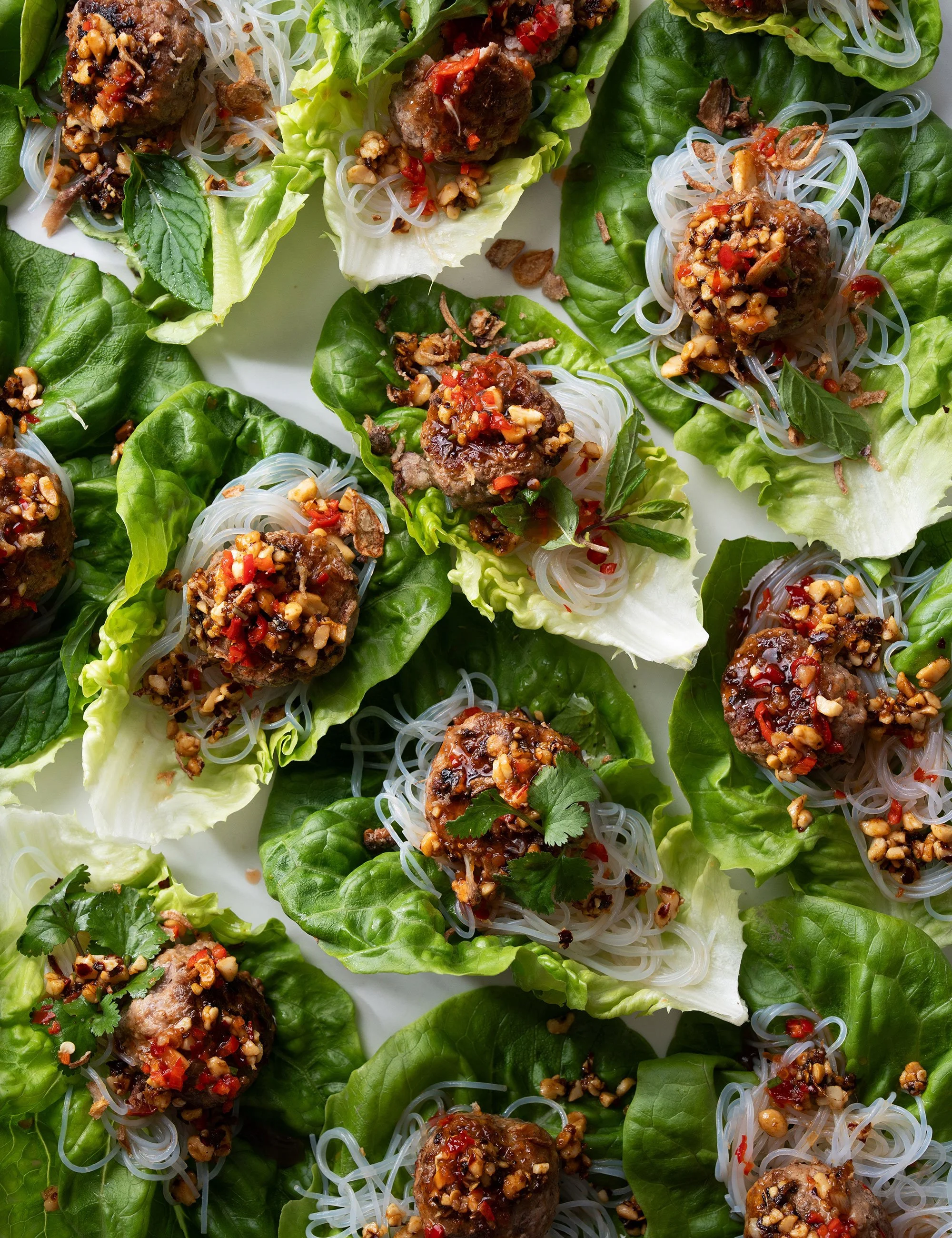 Green salad cups topped with roasted vegetables and herbs.
