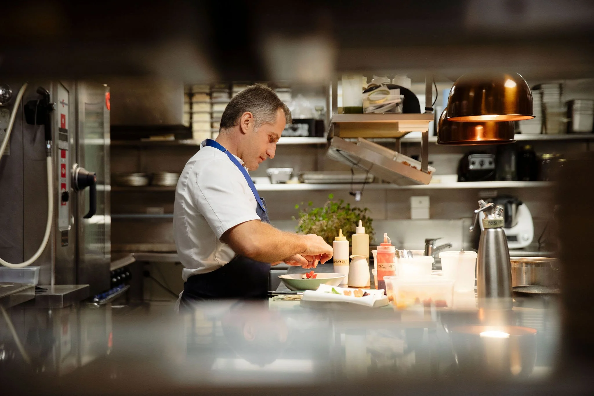 Chef working in a commercial kitchen during food preparation.