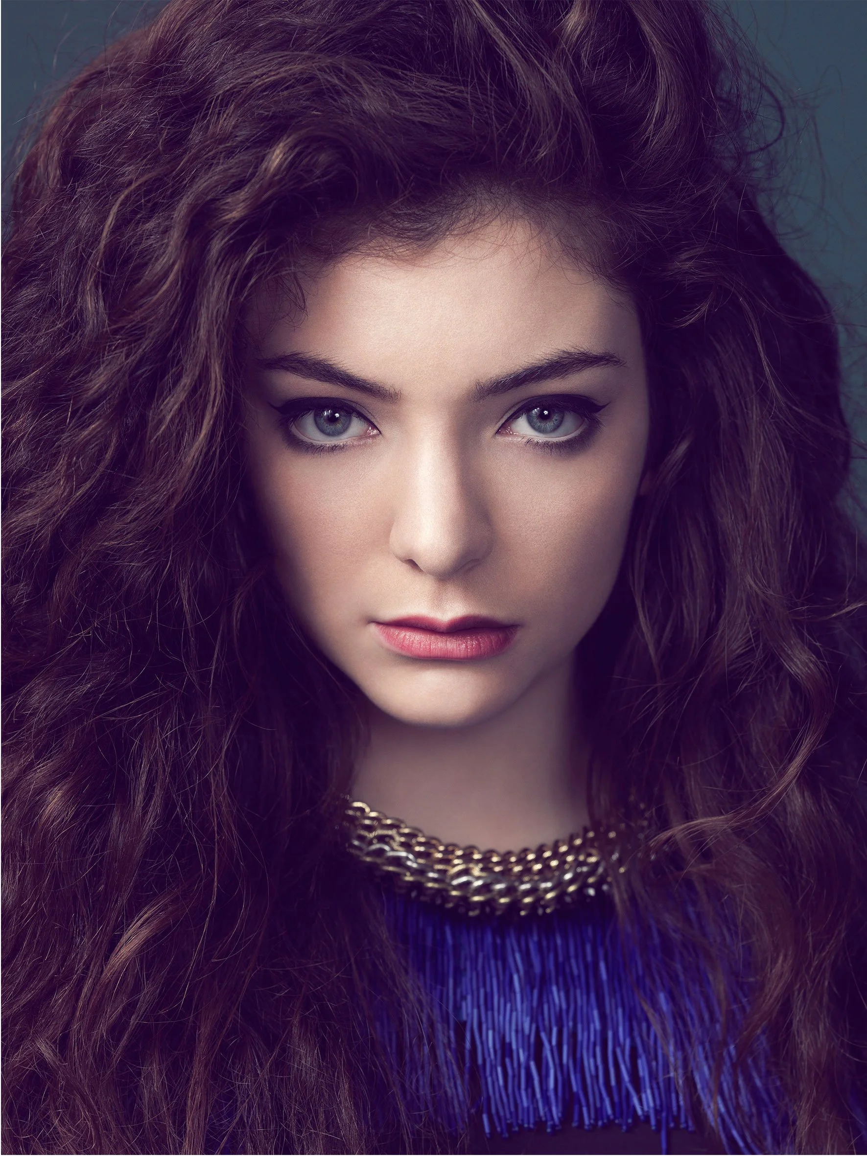 Editorial portrait of Lorde with strong eye contact, dark curly hair and polished fashion styling.