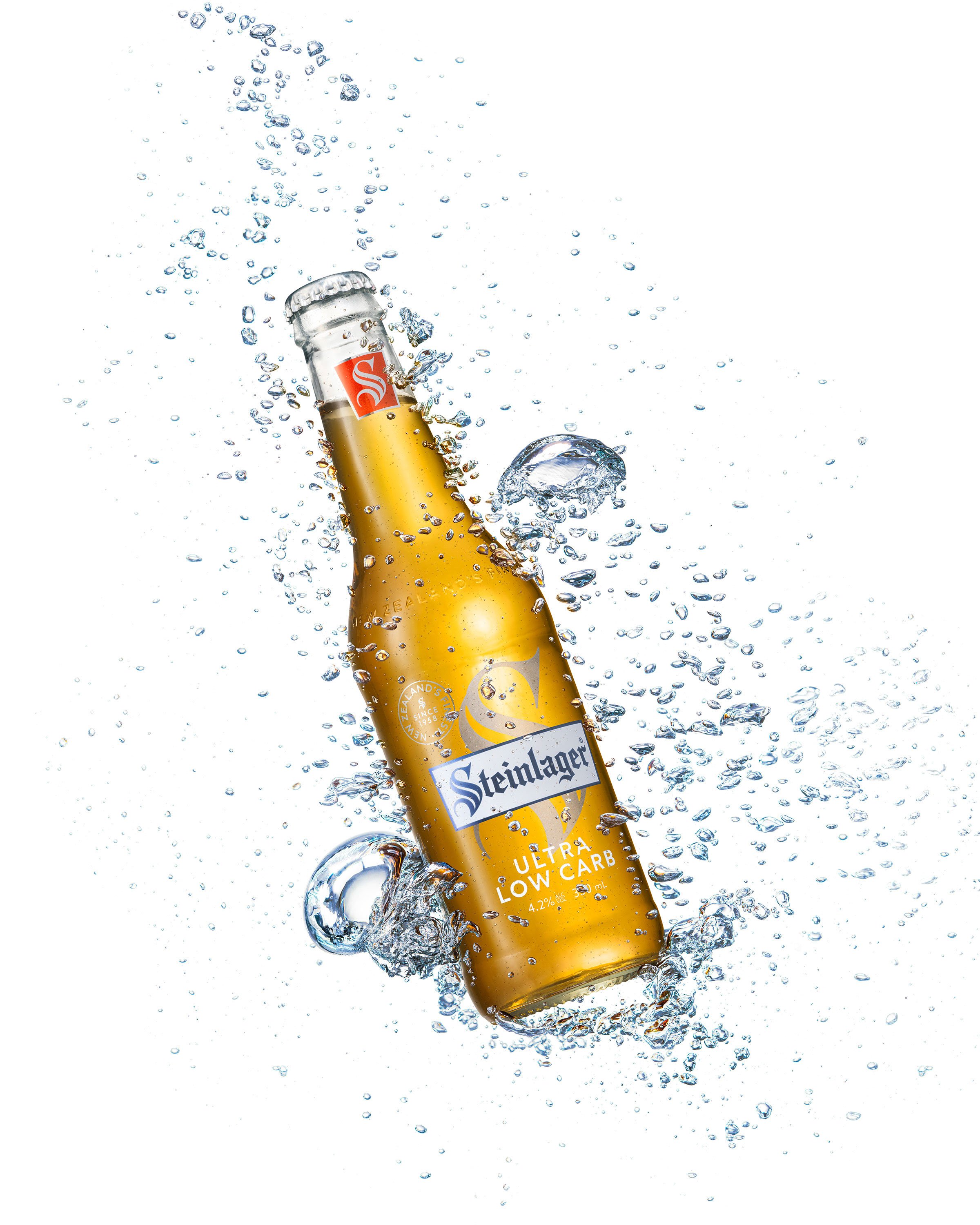 High-key product photograph of Steinlager Ultra Low Carb with suspended splash detail, giving the image a crisp and refreshing feel.