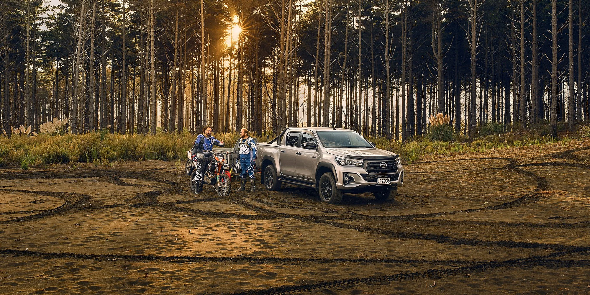 Automotive and sport lifestyle photography featuring a Toyota Hilux, motocross riders and warm evening light in a rugged outdoor location.