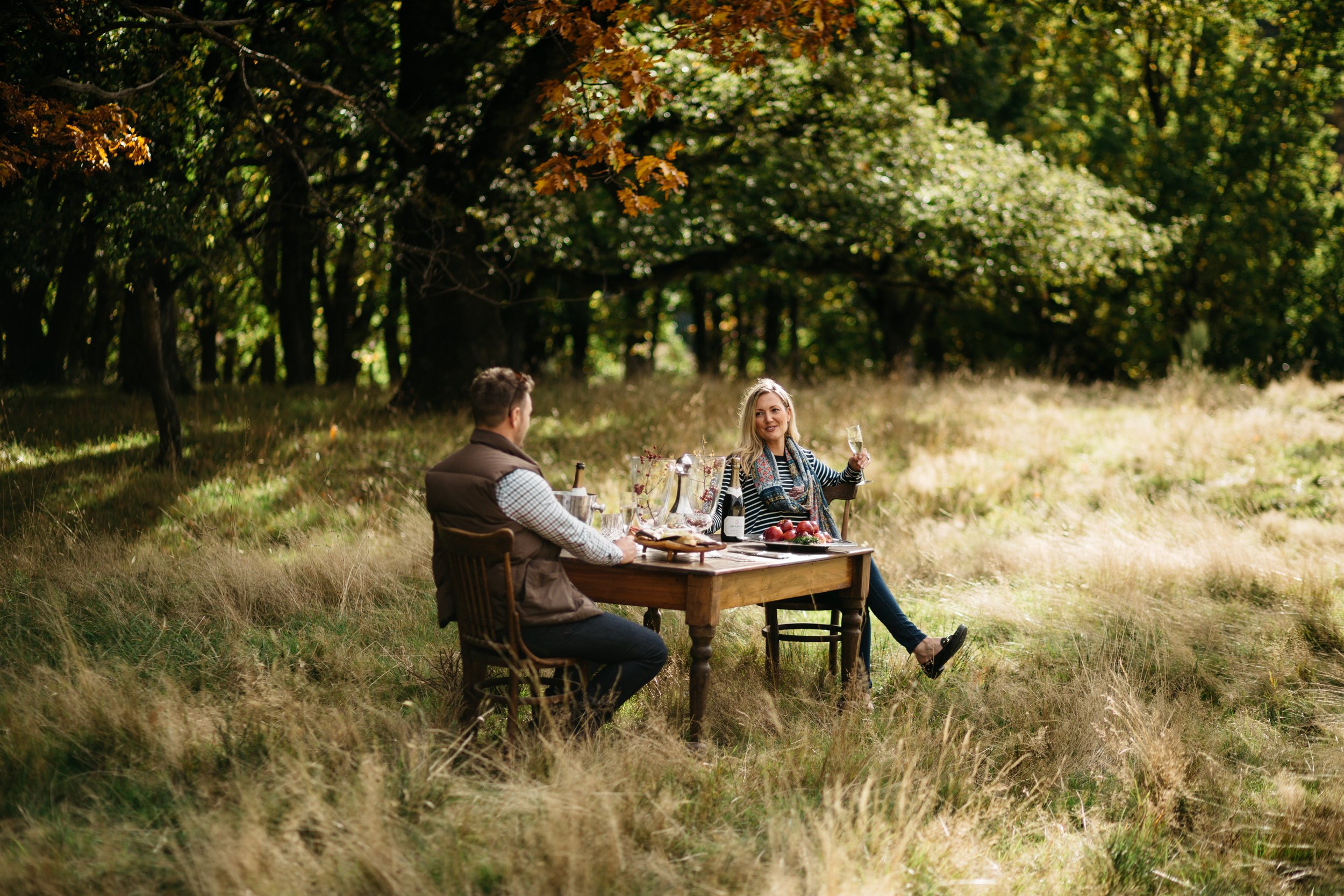 Guests seated at an outdoor picnic table in a garden setting.