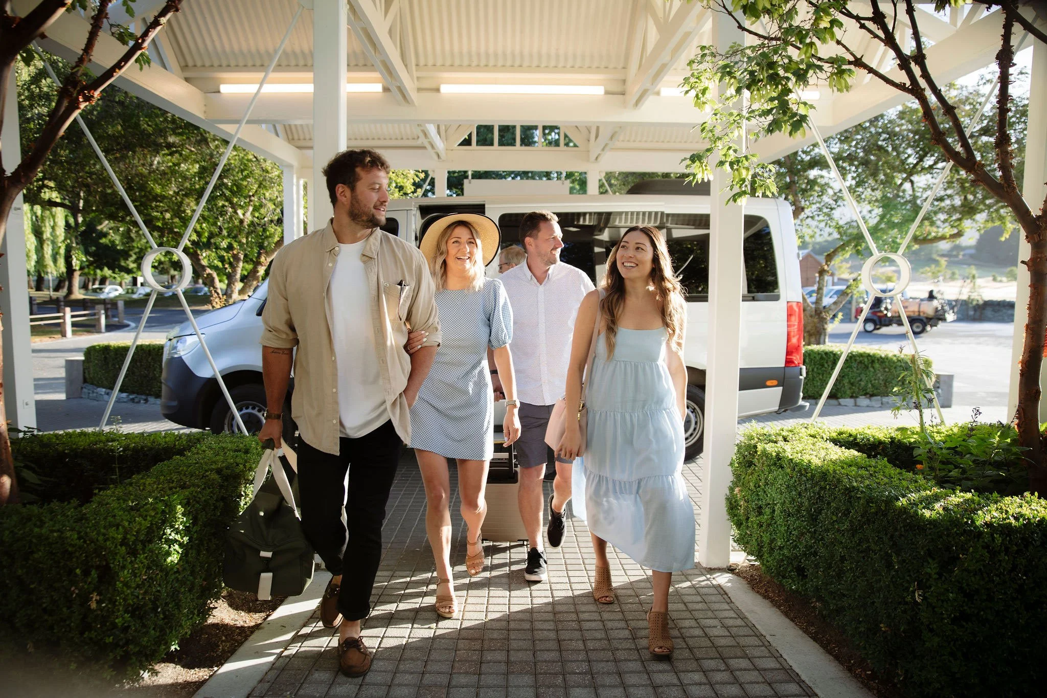 Group arriving at a resort entrance with luggage for a luxury Queenstown accommodation campaign.