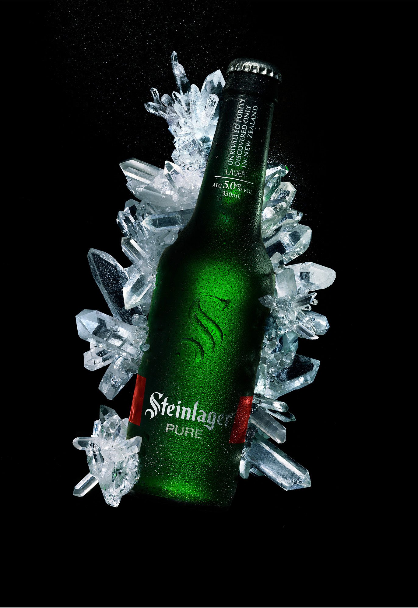 Dramatic product image of a chilled Steinlager Pure bottle surrounded by crystal-like ice, emphasizing freshness and premium styling.
