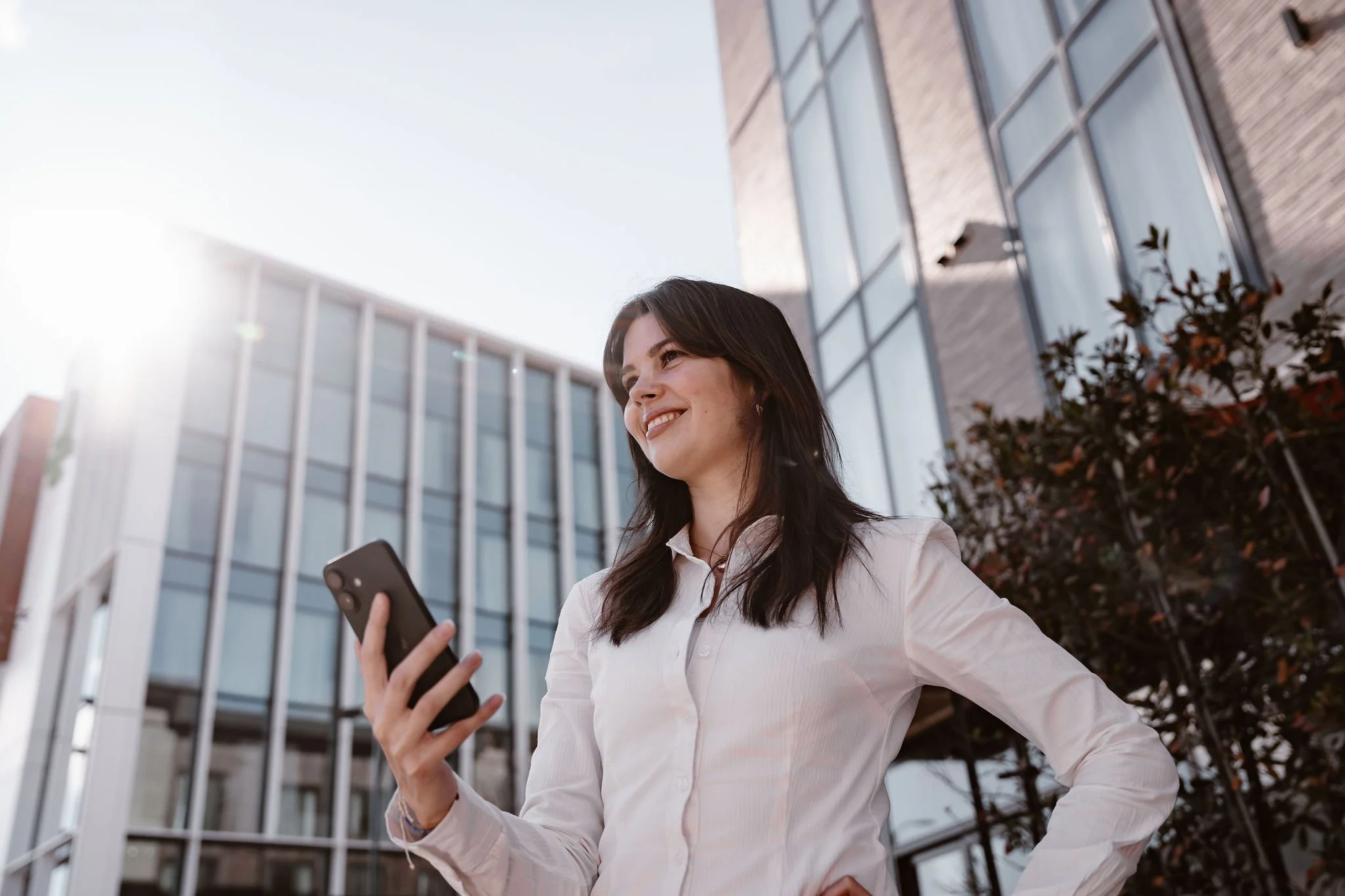 Woman using a phone outside a modern building in a lifestyle portrait.