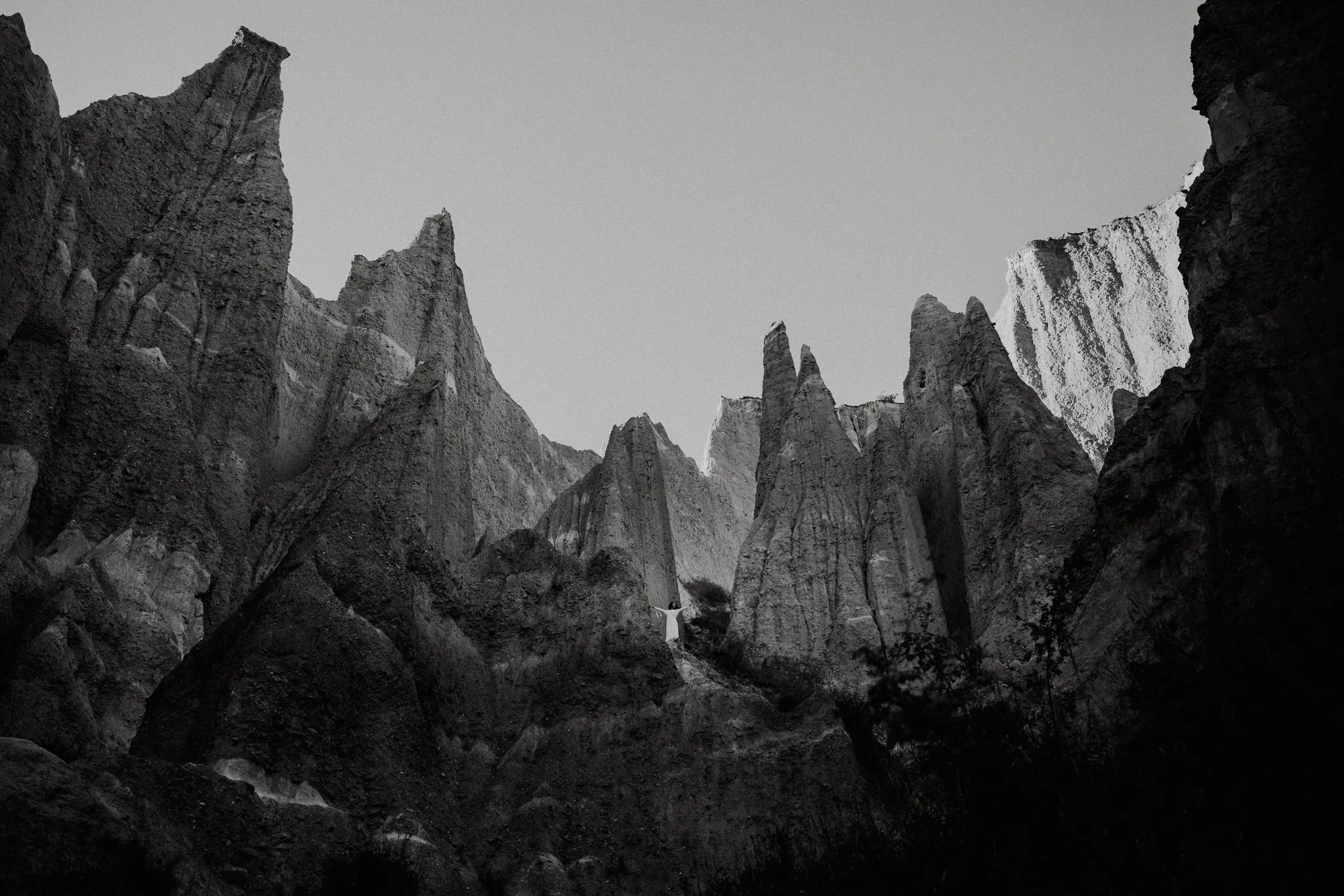 Black-and-white landscape of dramatic rock spires and mountain formations.